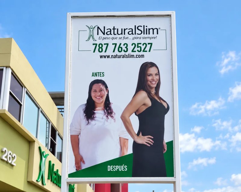 Letrero de poste de NaturalSlim con fotos de antes y después y el teléfono