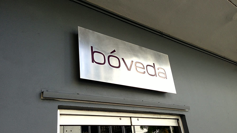 Illuminated Bóveda sign on a dark panel