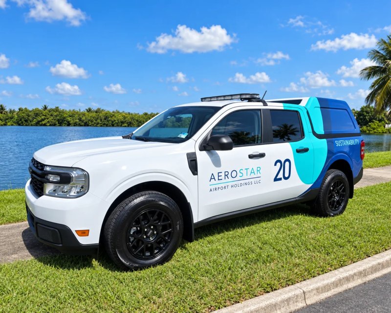 Pickup blanca de Aerostar Airport Holdings rotulada con franjas azules y número de unidad