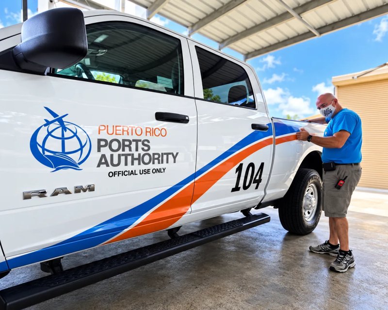 Instalador aplicando la rotulación en la puerta de una pickup de la Autoridad de los Puertos